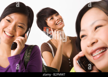 Tre giovani donne a parlare su telefoni cellulari e sorridente Foto Stock