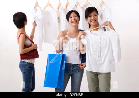 Tre giovani donne selezione di abiti in un negozio di abbigliamento Foto Stock