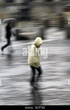 Persone che indossano impermeabile mantelli in Rain Foto Stock