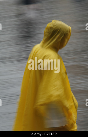Persona che indossa Giaccone impermeabile giallo capo in caso di pioggia Foto Stock