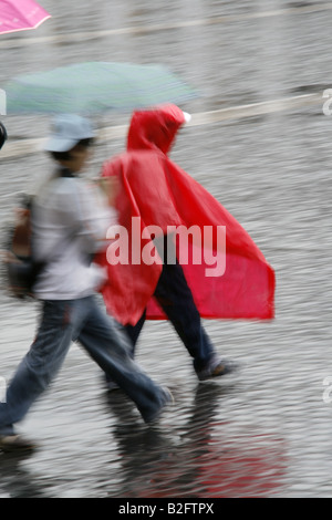 Persone che indossano impermeabile mantelli in Rain Foto Stock