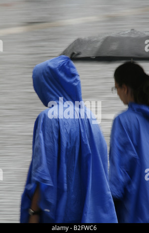 Persone che indossano impermeabile mantelli in Rain Foto Stock