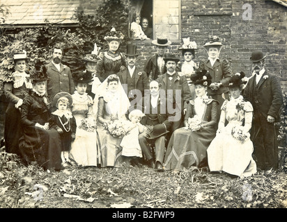 1899 Fotografia, matrimonio vittoriano gruppo. Posto all'aperto con Ponte e sposo nel mezzo, seduto in semicerchio, il tutto in abbigliamento vittoriano. Contatto con gli occhi. Foto Stock