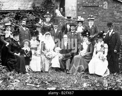 1899 Fotografia, matrimonio vittoriano gruppo. Posto all'aperto con Ponte e sposo nel mezzo, seduto in semicerchio, il tutto in abbigliamento vittoriano. Contatto con gli occhi. Foto Stock