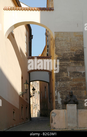 Una stretta di ciottoli stone street a Praga con edifici collegati da archi su entrambi i lati della strada e la statua di PM Churchill Foto Stock