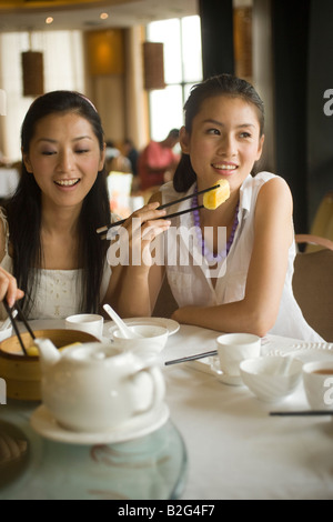 Due giovani donne mangiare dim sum in un ristorante Foto Stock