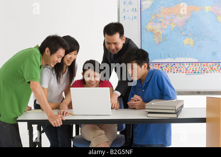 Il Professor utilizzando un computer portatile con i suoi studenti in classe Foto Stock