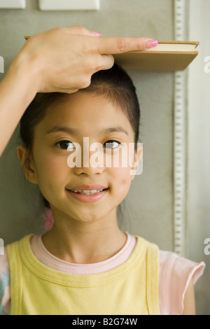 Donna ragazza di misurazione dell'altezza contro una parete Foto Stock