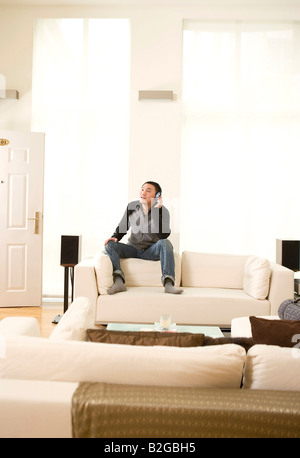Vista di una metà uomo adulto ascoltando la musica nella stanza vivente Foto Stock