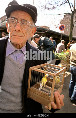 L'uomo azienda birdcage con canarini a un mercato Foto Stock