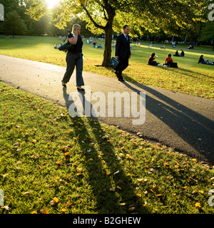 Due persone di affari casting ombre lunghe a piedi di sera autunno sunshine in St James Park Londra Inghilterra REGNO UNITO Foto Stock