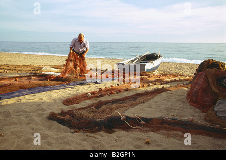 Vecchio Pescatore diffondere le reti sulla sabbia. Bolnuevo beach. Murcia Provincia. Spagna. Foto Stock