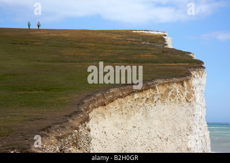 Due persone a piedi lungo il bordo delle Scogliere Bianche di Dover, Inghilterra Foto Stock