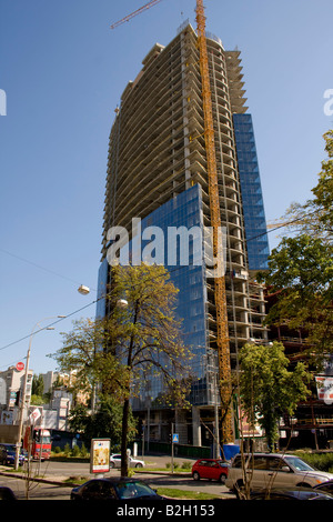 Complesso multifunzionale Gulliver in costruzione a Kiev con una gru e alberi circostanti, contro un cielo azzurro. Foto Stock
