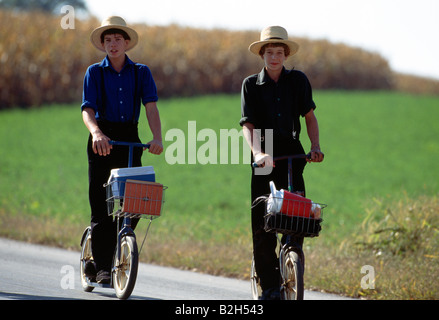 I bambini Amish in pianura tradizionale abbigliamento su scooter sul loro modo a casa da scuola, Lancaster County, Pennsylvania, STATI UNITI D'AMERICA Foto Stock