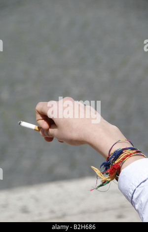 Dettaglio uomo adolescente holding sigaretta in città Foto Stock