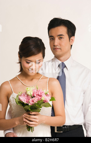 Ritratto di uno sposo in piedi con il suo braccio intorno a una sposa Foto Stock