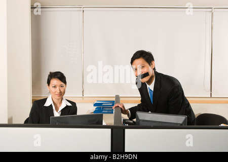 Ritratto di un imprenditore con un nastro adesivo sulla bocca e imprenditrice seduto accanto a lui Foto Stock