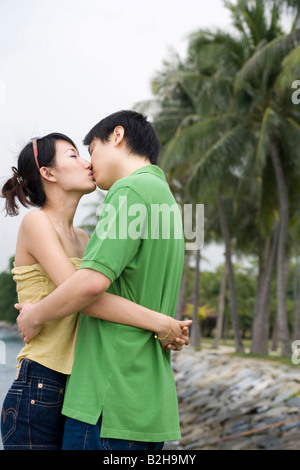 Metà adulto giovane kissing ogni altro sulla spiaggia Foto Stock