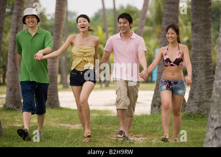 Due coppie di camminare sulla spiaggia con la tenuta tra di loro le mani Foto Stock