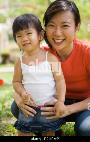 Ritratto di un adulto medio donna sorridente con la figlia in un parco, Singapore Foto Stock