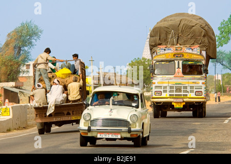 Una compressa di vista prospettica del traffico su strada con un sovraccarico autocarro, la gente del posto su un pick-up e un ambasciatore auto. Foto Stock