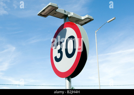 30 30mph miglia per ora cartello stradale con luci a lato della strada in una giornata di sole close up Foto Stock