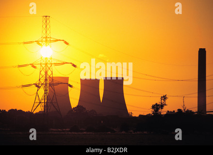 Regno Unito. Inghilterra, Berkshire. Silhouette di Didcot power station nelle torri di raffreddamento ed elettricità pilone con sole di sera. Foto Stock