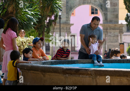 MEXICAN adulti e bambini giocare vicino a una fontana nella storica città di Guanajuato MESSICO Foto Stock