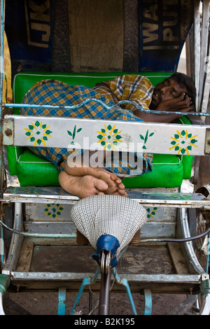 Uomo dorme sul suo risciò ciclo in Kumbakonam India del Sud Foto Stock