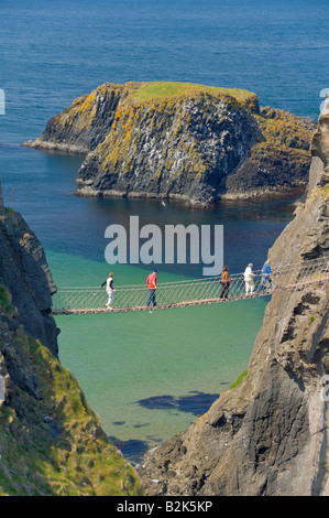 Turisti attraversando il Carrick a rede ponte di corde di Carrick isola Ballycastle County Antrim Irlanda del Nord Regno Unito GB EU Europe Foto Stock