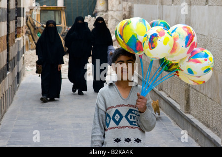 Le donne musulmane di indossare burka e ragazzo palloncini di vendita al di fuori di Umayyad moschea a Damasco in Siria Foto Stock