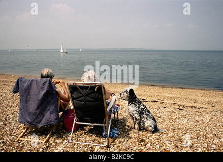 Coppia di anziani sulla sdraio cane che guarda al mare su una spiaggia spiaggia sull isola di Wight 1991 Foto Stock