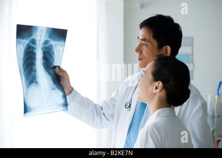 Due medici esaminando un X-Ray relazione Foto Stock