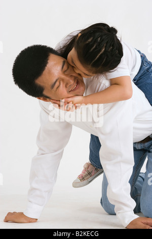 Ragazza a cavallo trasportato su suo padre e sorridente Foto Stock