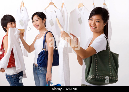 Tre giovani donne selezione di abiti in un negozio di abbigliamento Foto Stock