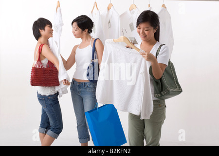 Tre giovani donne selezione di abiti in un negozio di abbigliamento Foto Stock