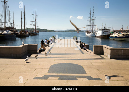 Persone rilassarsi vicino al veterano barche ormeggiate nel porto di Oslo Foto Stock