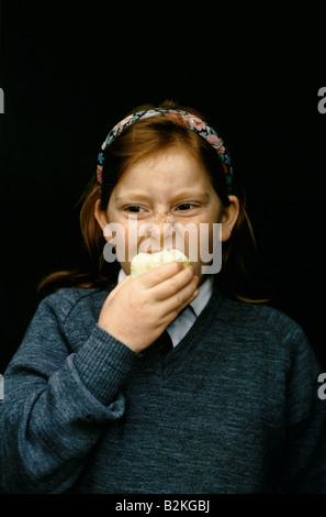 La scuola primaria ragazza di mordere in un Apple Foto Stock