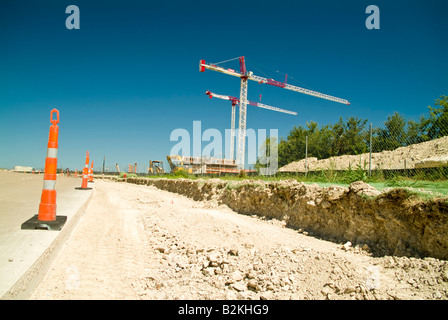 Sicurezza o coni segnaletici con due grandi gru sullo sfondo di un sito in costruzione Foto Stock