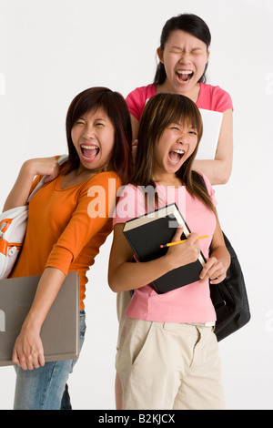 Ritratto di femmina di tre studenti universitari in piedi e gridare insieme Foto Stock