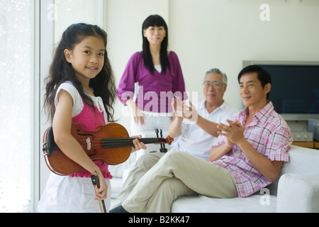 I membri della famiglia apprezzare una ragazza suona il violino Foto Stock