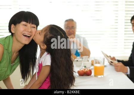 Close-up di una ragazza baciare la sua madre ad un tavolo per la colazione Foto Stock