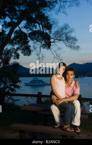 Ritratto di una metà donna adulta seduta sul giro di un giovane uomo a mare Foto Stock