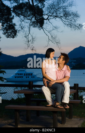 Metà donna adulta seduta sul giro di un giovane uomo a mare Foto Stock