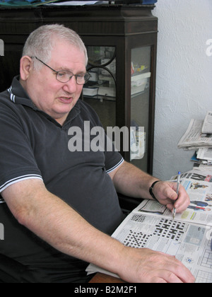 Uomo anziano facendo un cruciverba usando il suo cervello per mantenerlo attivo Foto Stock