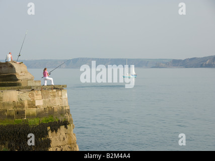 Donna caucasica in piedi sulla parete del porto di Scarborough pesca marittima. Foto Stock