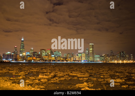 Lo skyline di Chicago, IL brilla in una fredda notte invernale come il ghiaccio galleggia nel lago Michigan. Foto Stock