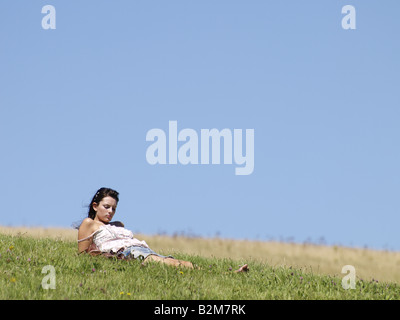 Giovane donna a prendere il sole su una coperta di erba hill Foto Stock