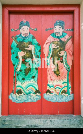 Rosso di doppie porte in legno con dio artistico figure a stretto ancestrale Cinese Tempio del clan, Cheah Si Sek Tek Tong, in Georgetown, Penang, Malaysia Foto Stock